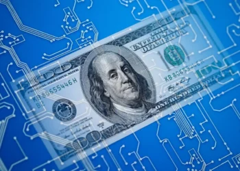 A $100 bill featuring Benjamin Franklin is overlaid on a blue background with white circuit board patterns, symbolizing the intersection of finance and digital money. | COYYN