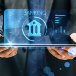 A person in business attire holds a tablet displaying a stylized bank icon and the word "BANKING" in prominent letters. Surrounding the bank icon are various graphical data elements and charts, all glowing with blue accents, symbolizing the future of digital banking. | COYYN