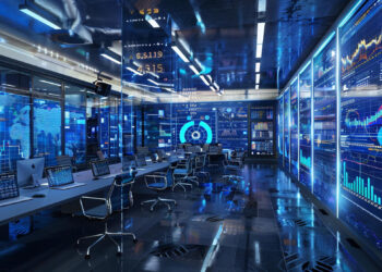 A modern control room, akin to a Digital Innovation Hub, boasts multiple computer stations with screens showcasing graphs, charts, and world maps. Blue lighting enhances the high-tech ambiance, while sleek chairs are arranged neatly around the desks. | COYYN