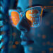 A person wearing glasses examines a digital screen displaying reflective code and numbers, immersed in a blue and orange glow. The futuristic scene hints at an AI-powered cyber security assessment, highlighting a tech-focused atmosphere. | COYYN