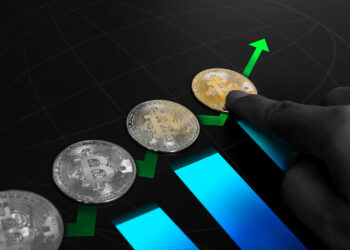 A hand points to a gold bitcoin among three silver bitcoins, with green arrows and blue bars rising upward—an image perfect for the crypto niche, symbolizing cryptocurrency growth or increasing bitcoin value. | COYYN