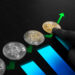 A hand points to a gold bitcoin among three silver bitcoins, with green arrows and blue bars rising upward—an image perfect for the crypto niche, symbolizing cryptocurrency growth or increasing bitcoin value. | COYYN