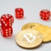 Three red dice and two stacked gold coins with Bitcoin symbols on a white background evoke a sense of risk, much like playing Bitcoin Baccarat, where cryptocurrency meets the thrill of gambling. | COYYN