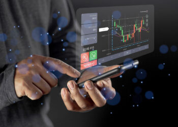 A person uses a smartphone with a futuristic, transparent screen displaying a financial chart, trading options, and digital data, surrounded by blue glowing particles. | COYYN
