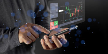 A person uses a smartphone with a futuristic, transparent screen displaying a financial chart, trading options, and digital data, surrounded by blue glowing particles. | COYYN