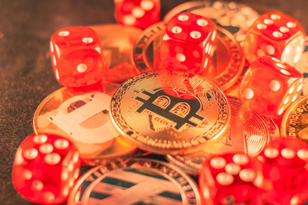 Red dice surround and rest on top of various cryptocurrency coins, including Bitcoin and Litecoin, symbolizing the element of risk or chance found in both cryptocurrency investments and Bitcoin casinos. | COYYN