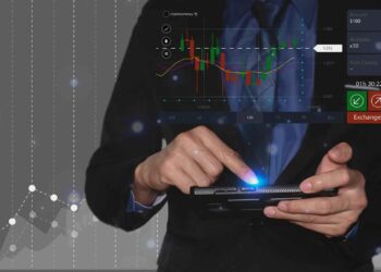 A person in a suit uses a tablet displaying a digital stock trading chart and financial data.