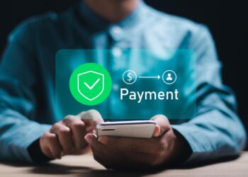 A person wearing a blue shirt uses a smartphone, with a digital overlay showing a checkmark, dollar sign, arrow, user icon, and the word "Payment" indicating a secure online transaction. | COYYN