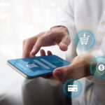 A person uses a smartphone for e-payment, with digital icons for shopping cart, security, and credit card floating nearby, symbolizing online shopping and secure transactions. | COYYN