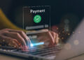 Hands typing on a laptop keyboard with a floating digital payment form overlay, showing card details and a green shield icon—suggesting secure online payment and highlighting 3 important things players should know before signing up to a new online casino. | COYYN