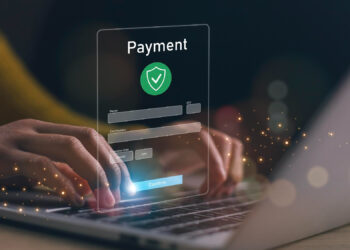 Hands typing on a laptop keyboard with a floating digital payment form overlay, showing card details and a green shield icon—suggesting secure online payment and highlighting 3 important things players should know before signing up to a new online casino. | COYYN