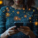 A woman holding a smartphone with glowing digital icons and dollar signs surrounding her, representing online banking, financial transactions, and digital currency. The background is blurred and dark. | COYYN