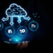 A hand holds a smartphone with a glowing cloud computing icon above it, surrounded by digital folder, book, gear, and document icons, representing cloud data and technology connectivity. | COYYN